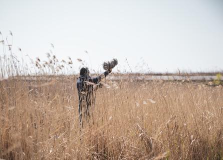 Photography of a person standing in a field with recording equipment