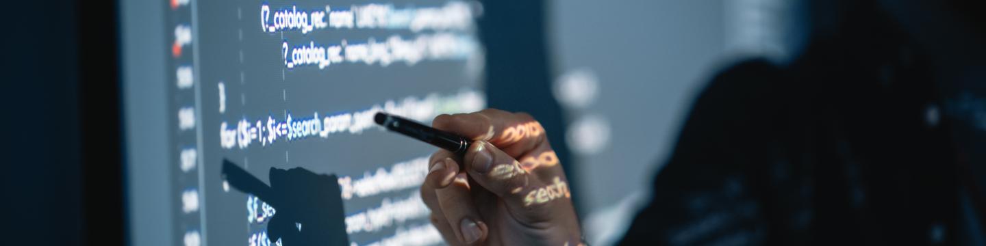 A man pointing at an image of code being projected on a wall