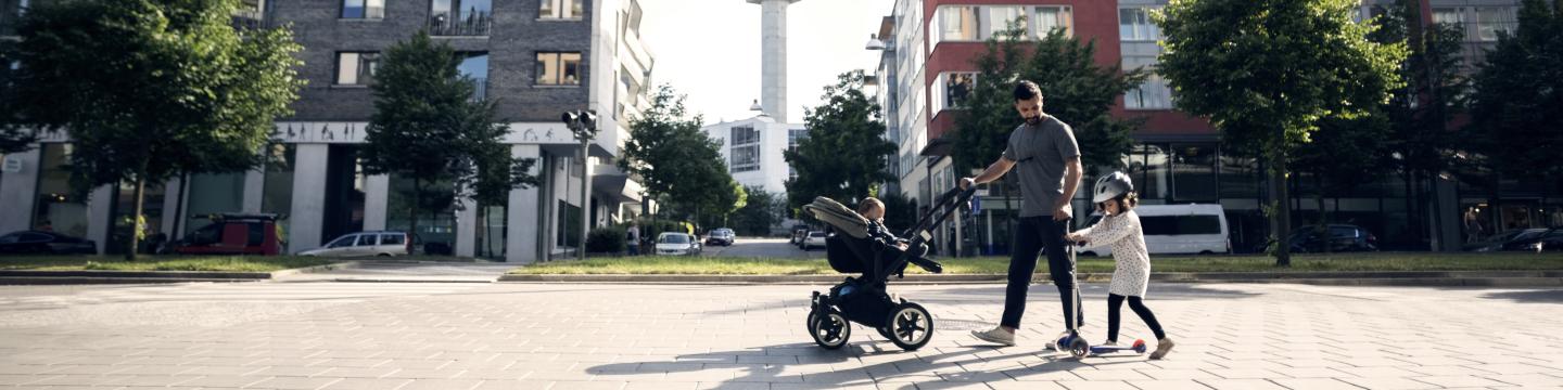 A man walking in a city with a stroller and a child