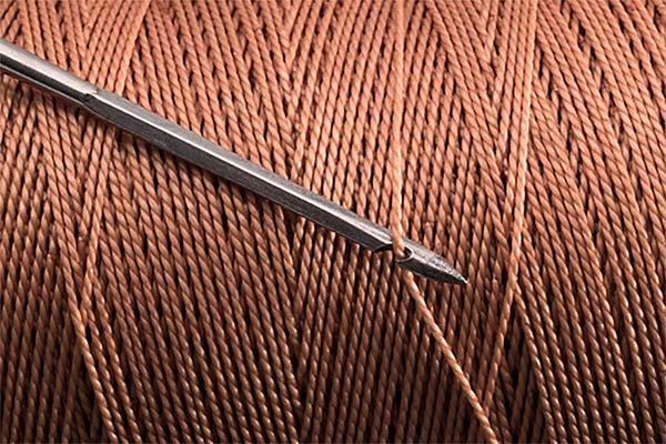 Brown thread on spool and knitting needle