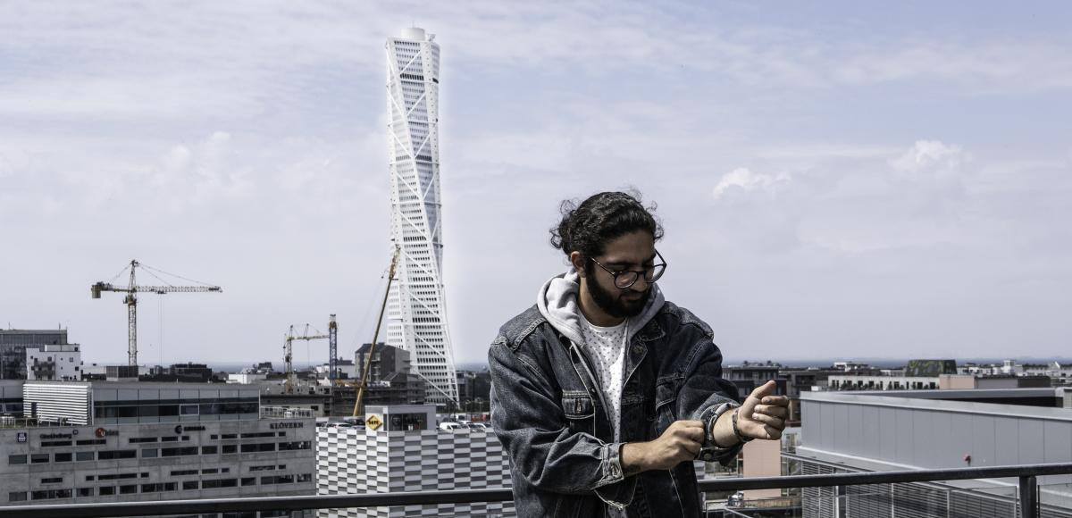 Nima Goniband - software engineer at AFFRY standing in front of Turning Torso in Malmö and sorting out 