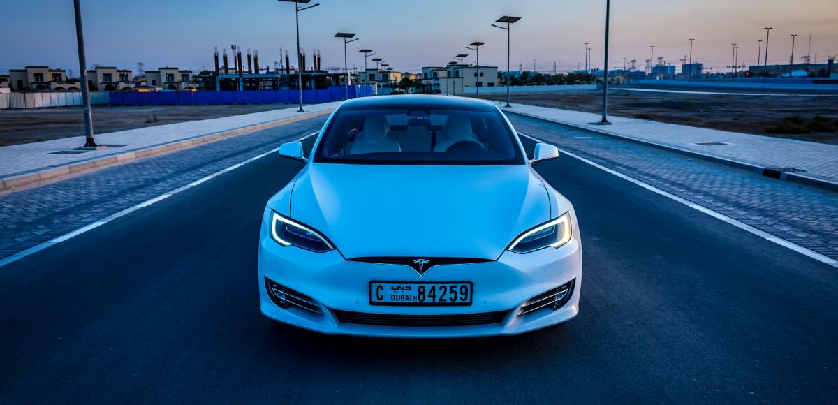 White Tesla driving in Dubai at dusk