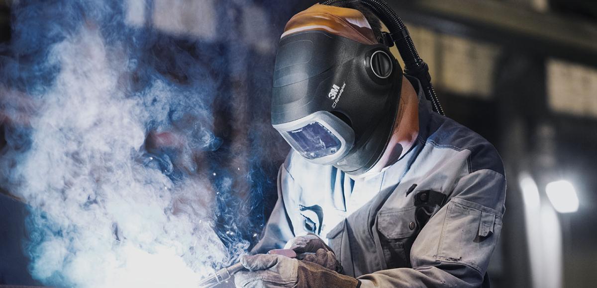 person welding wearing a helmet and creating a cloud