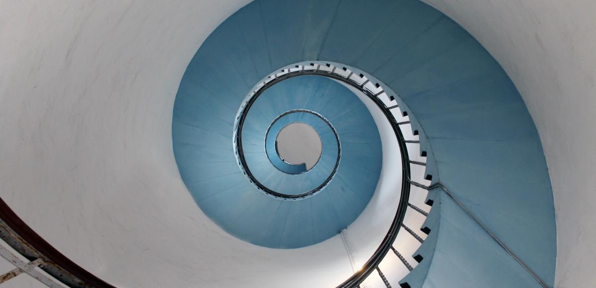 Spiral staircase looking upwards in ice blue and white with cast iron railings