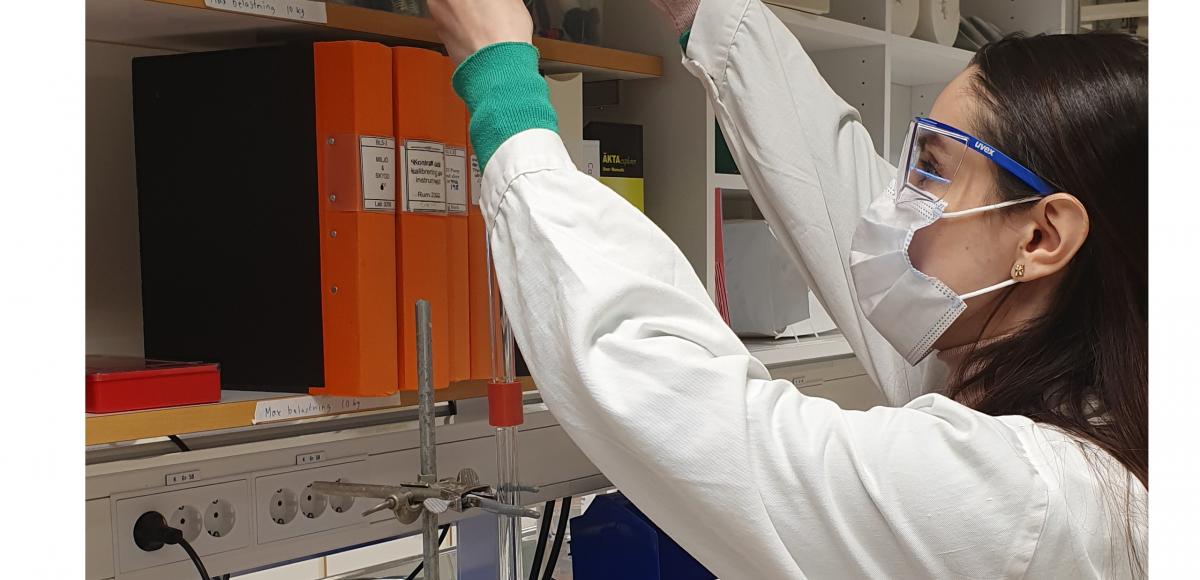 Photo of Raya Zamil at her job in lab environment wearing laboratory safety attire