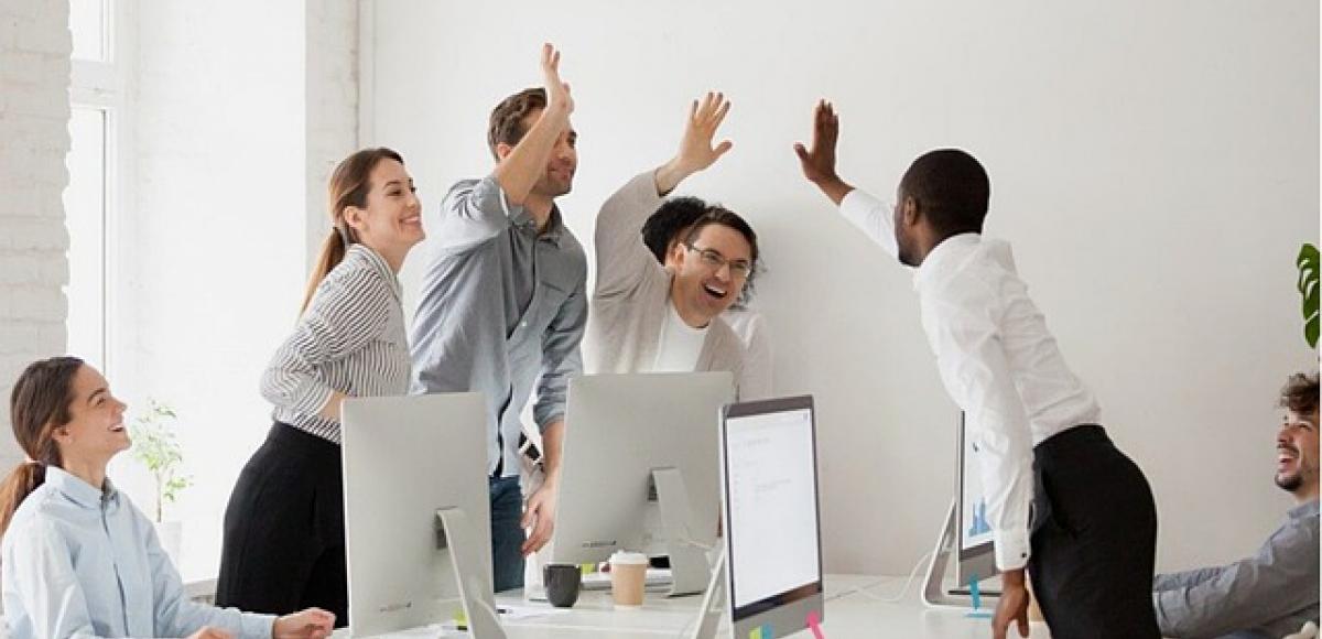 People around working table raise hands in happiness