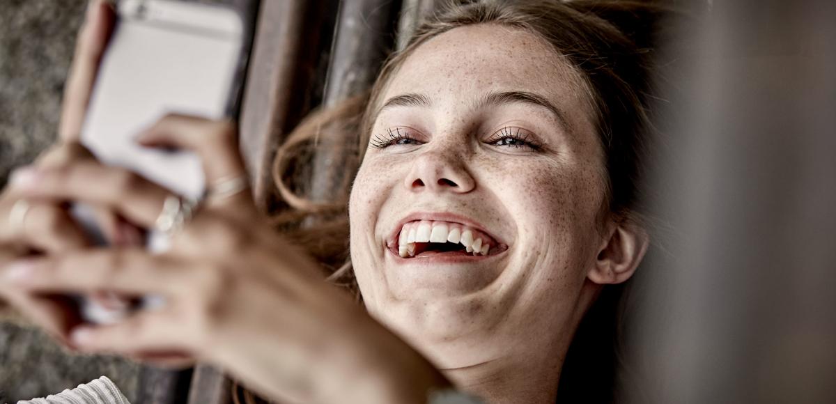 Young person with phone laughing