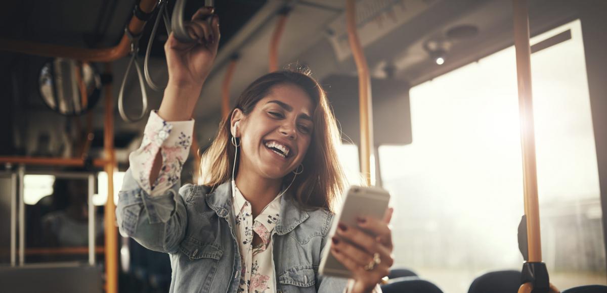 Young woman laughing while listening to music on a bus