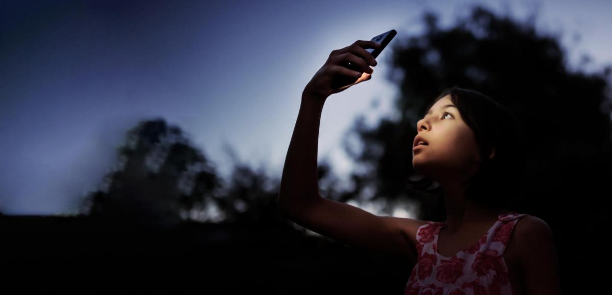 Girl with phone in dark outdoors