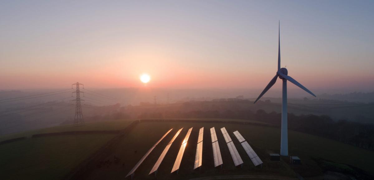 wind turbine next to solar panels in early morning light