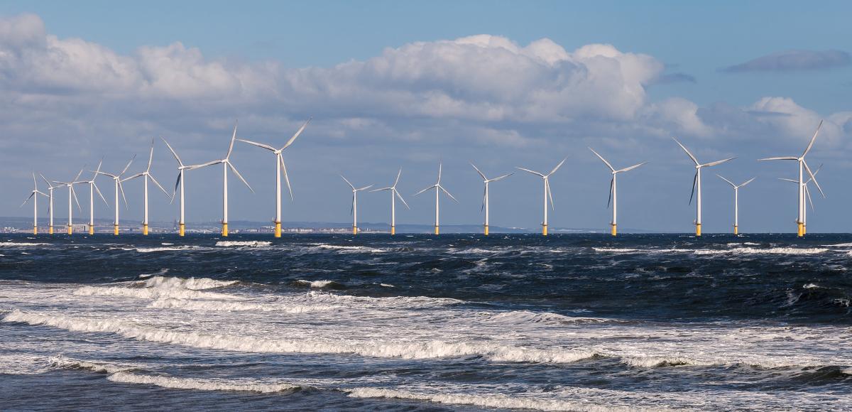 Lines of offshore wind turbines in the rolling surf off the North Sea coast