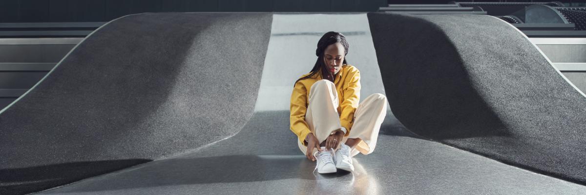 Woman tying shoelaces, white trainers, yellow jacket