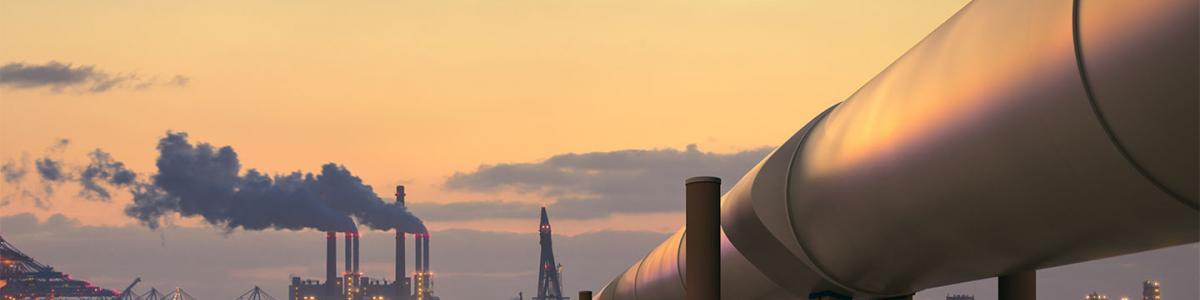 Oil pipeline in industrial district with factories at dusk