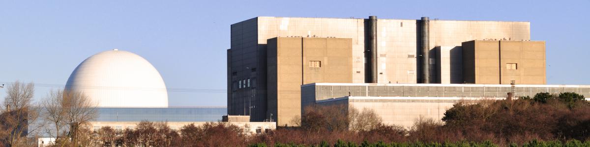 White nuclear reactor dome and beige building against a blue sky