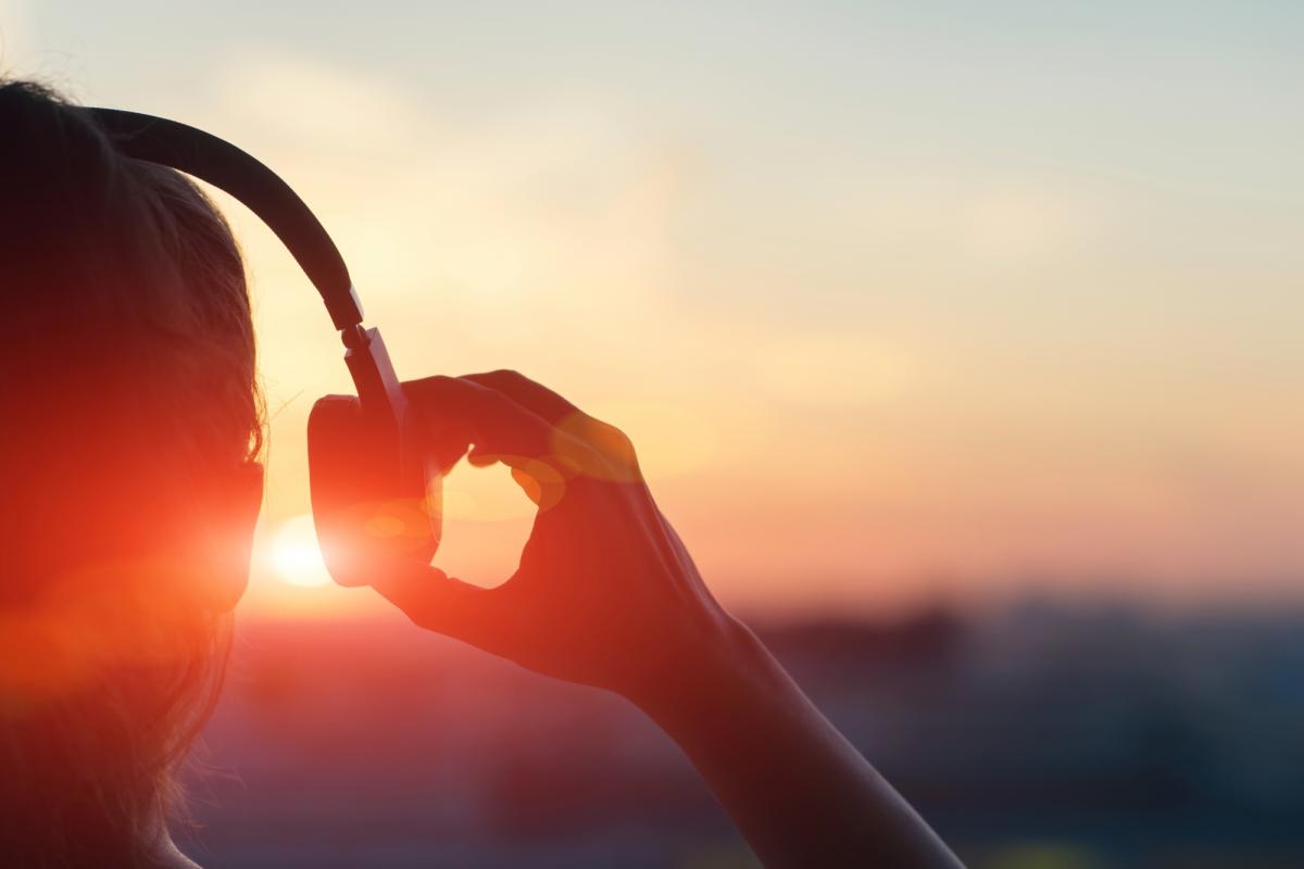 Girl in headphones listening to music in the city at sunset
