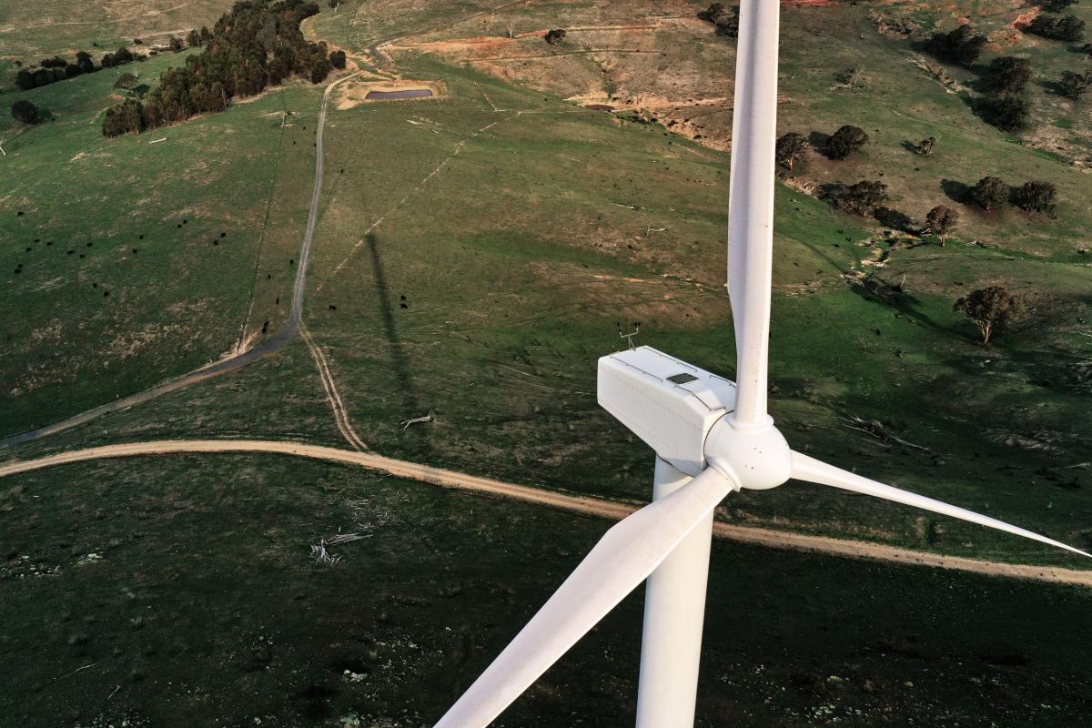Arial shot of a wind turbine on a backdrop of green fields