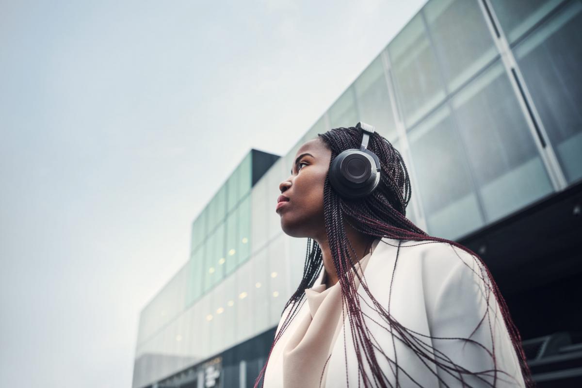Woman with headphones in urban business setting looking up