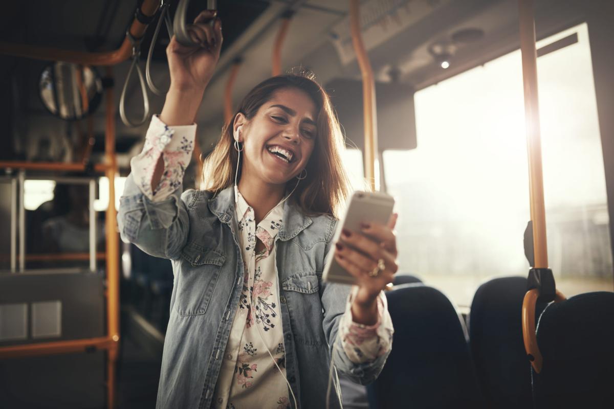 Woman at a buss looking at here phone and smiling
