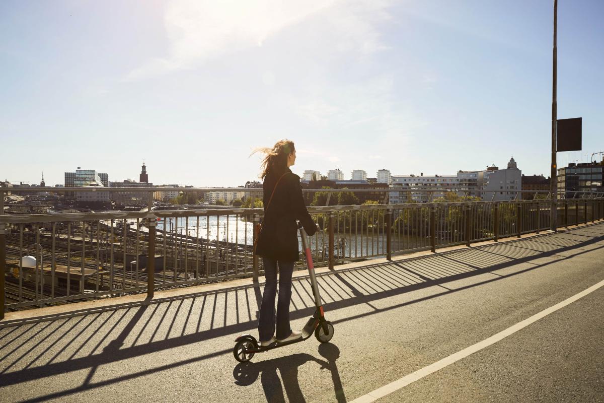 woman on electric scooter going over a bridge