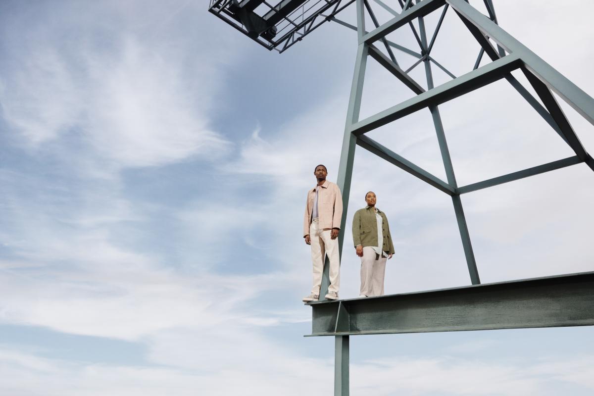 Expansive light blue-sky backdrop, with a man and a woman in the foreground standing on a crane