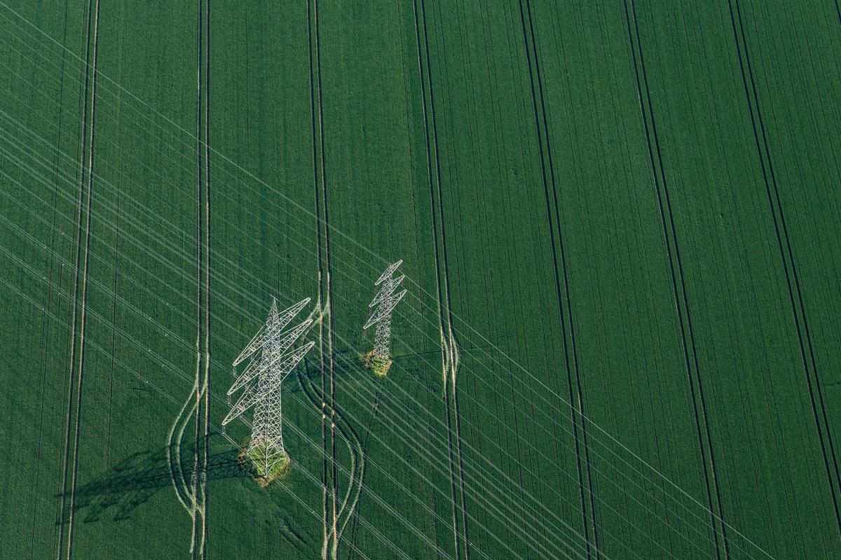 air-photo of a power line crossing green fields.