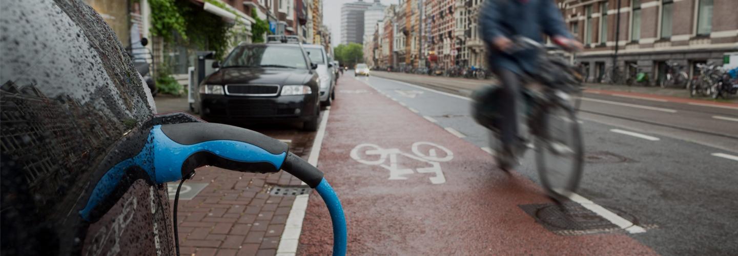 an electric car charging and a cyclist 