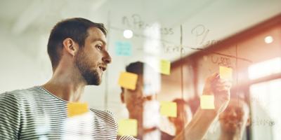 Man consulting others about plans with post-it note