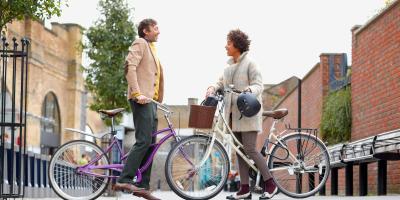 Two people on bikes meeting in the street and talking