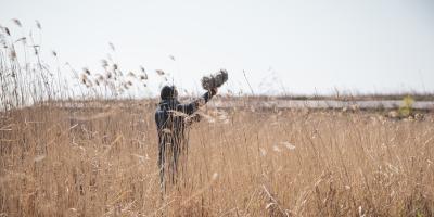 Photography of a person standing in a field with recording equipment