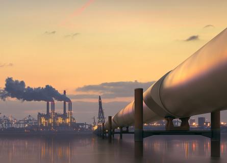 Oil pipeline in industrial district with factories at dusk