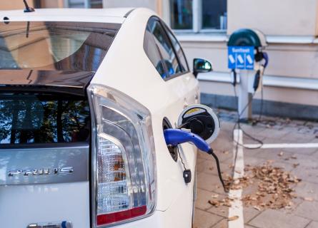 White electric car in Stockholm at charging station with blue plug