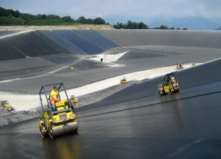 Tandem rolloers lining a reservoir with a layer of asphalt 