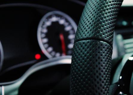 close up of black leather steering wheel inside vehicle