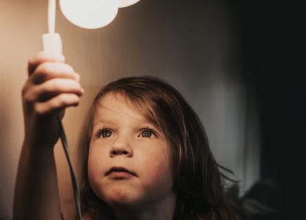 Small child reaching up to switch on light