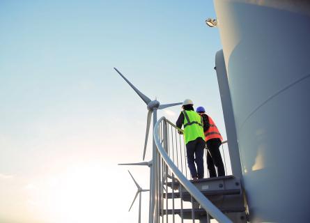 Two workers on staircase at the base of a wind turbine tower.