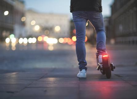 Person on an electric scooter at dusk with lights glowing