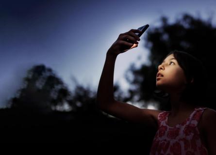 Girl with phone in dark outdoors