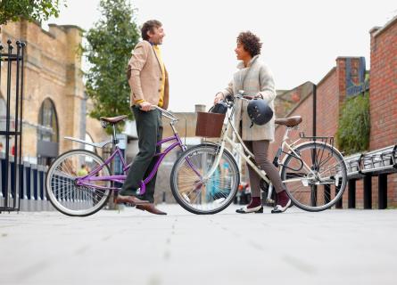 Two people on bikes meeting in the street and talking