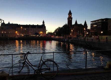 Cykel som lutar sig mot räcket vid vattnet under solnedgång