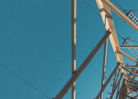 Looking up at an electricity pylon from beneath against blue sky