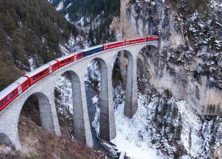 Obrázek zobrazuje vlak na viaduktu Landwasser na trati Albula