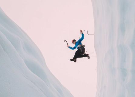 Resilient ice climber jumping over a ravine, having overcome any hesitant thoughts