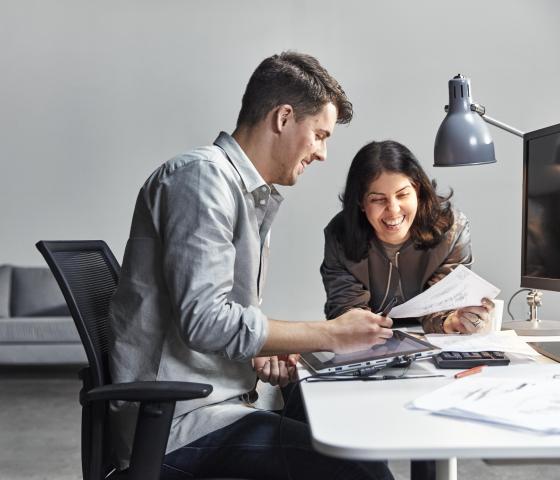 A man and woman reading technical drawings at a desk