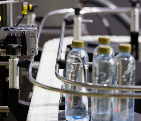Moving Bottles on Labelling machine for Industry. Color mark sensor installed on labelling machine in water production line in a factory