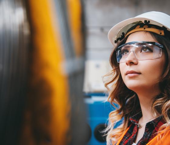 Young businesswoman white helmet googles industrial environment