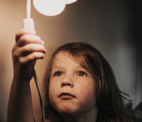 Small child reaching up to switch on light