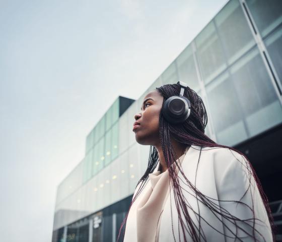 Woman with headphones in urban business setting looking up