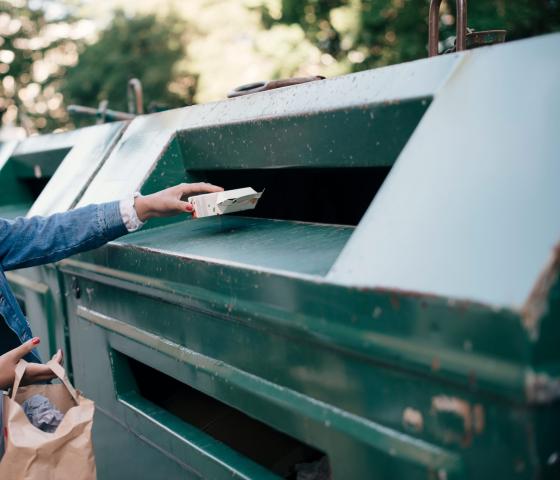 Teenage girl throwing carton in recycling bin
