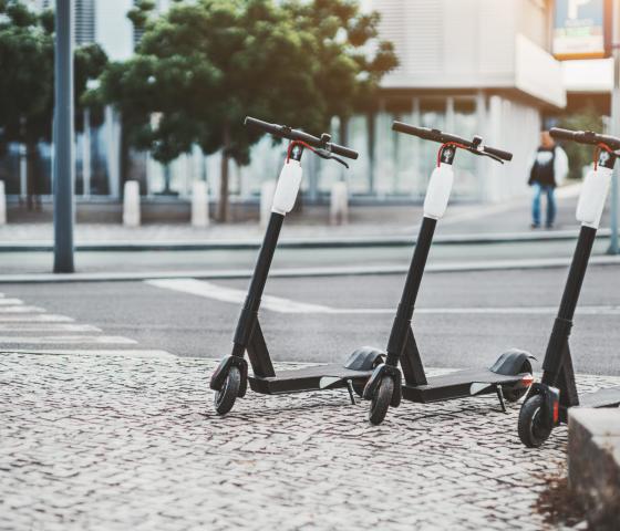 Three modern electric scooters bikes parked outside as part of circular economy