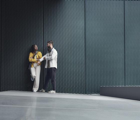 Man avd woman standing against a grey wall talking